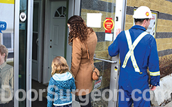 Worker & lady shopper enter store to purchase garage door repair parts, springs, hinges Devon.